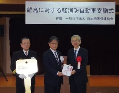 ＜目録、レプリカキーの贈呈＞(左から、間瀬消防団長、石黒町長、岩崎専務理事)