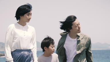 早朝の海辺を散歩する家族