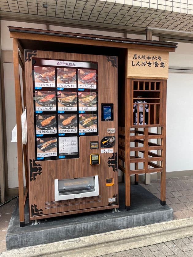 炭火焼干物定食で人気の『しんぱち食堂』が炭火焼冷凍干物の
自動販売機(ど冷えもん)を戸越公園通り商店街に設置　
～ロボット店長“ひものん”がお出迎え～