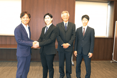 加計理事長（左端）とがっちり握手する田中さん（左から2人目）。その右隣は杉安元顧問、さらに吉澤顧問