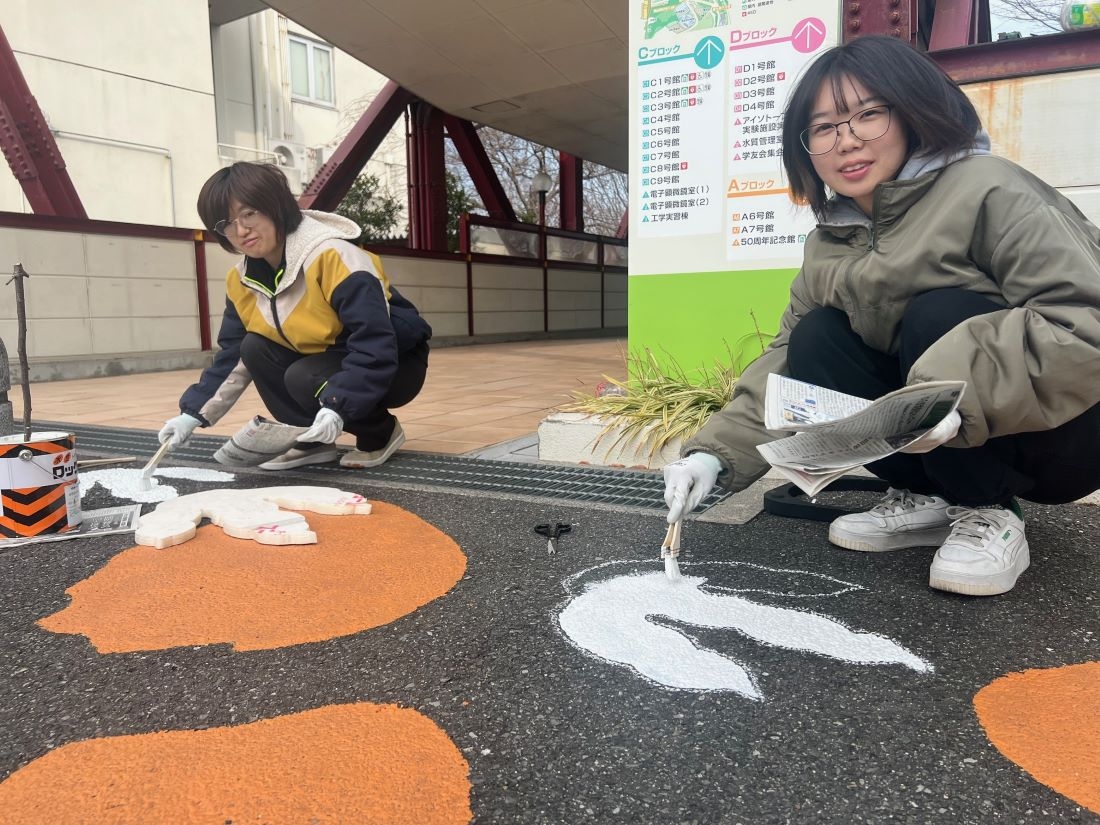 路面に足跡を描いていく(左から)窪井さんと齋藤さん