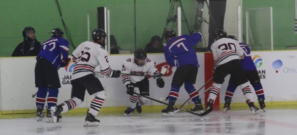 激しくぶつかり合う岡山(白色ユニフォーム)と滋賀の選手たち=アイスホッケー少年1回戦