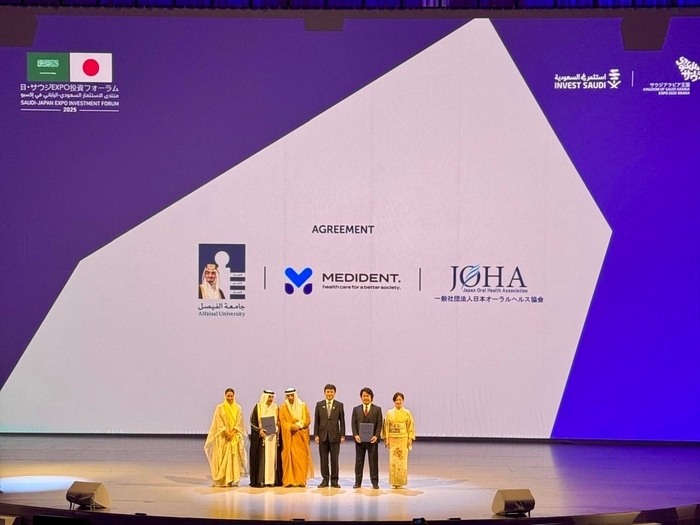 会場スクリーンに表示された提携3者のロゴ(Alfaisal University/MEDiDENT/日本オーラルヘルス協会)。公式プログラムとして壇上で合意。