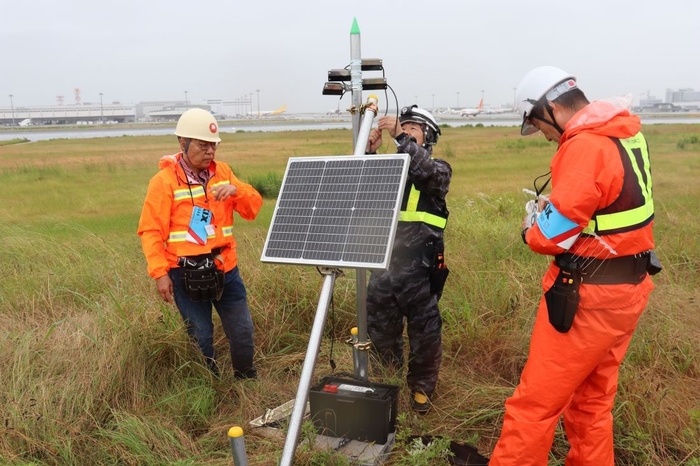 滑走路わきでバードソニックをくみ上げていく辻特坦教授(左)ら=写真はいずれも関西国際空港で6月3日撮影