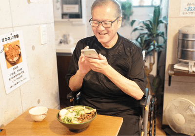 念願の「いこい」のうどんを前に、笑顔で写真を撮るご本人。待ちに待った一杯を楽しみました。