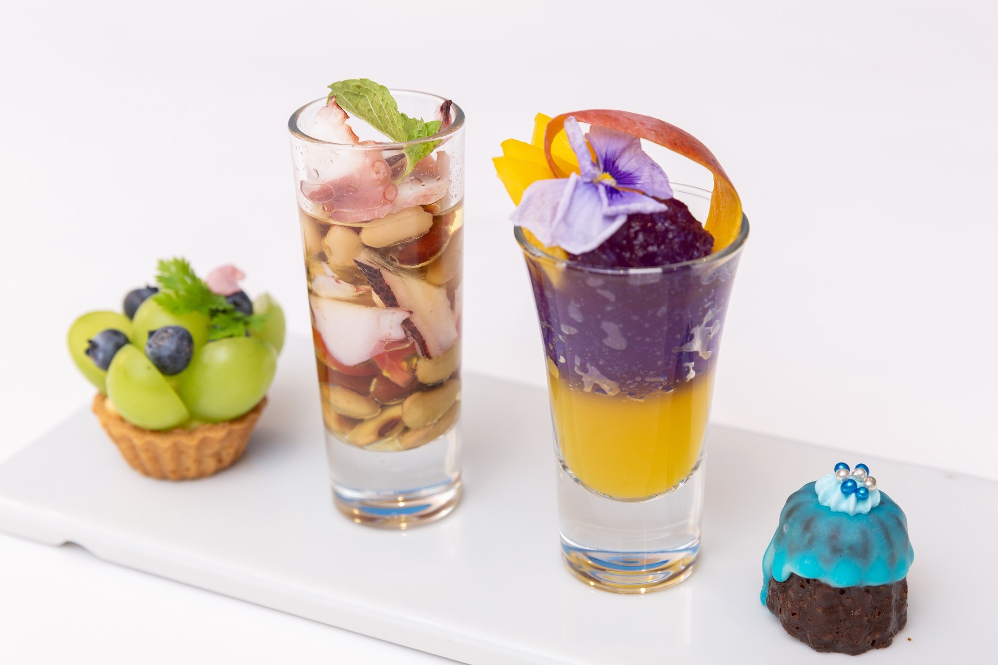 左から、「マスカットのタルト」、「タコとミックスビーンズのマリネ」 「マンゴーと青のジュレ」、「カヌレ」