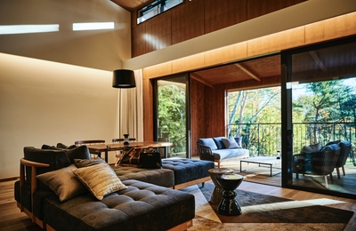 森に向かって窓が大きく開いたリビングルーム