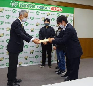 寄付金と目録を手渡す