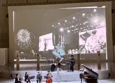 音楽劇「我ら地球人〜ダディとマザーの物語」公演より（スクリーンに9/26開催ライブ時の花火風景）