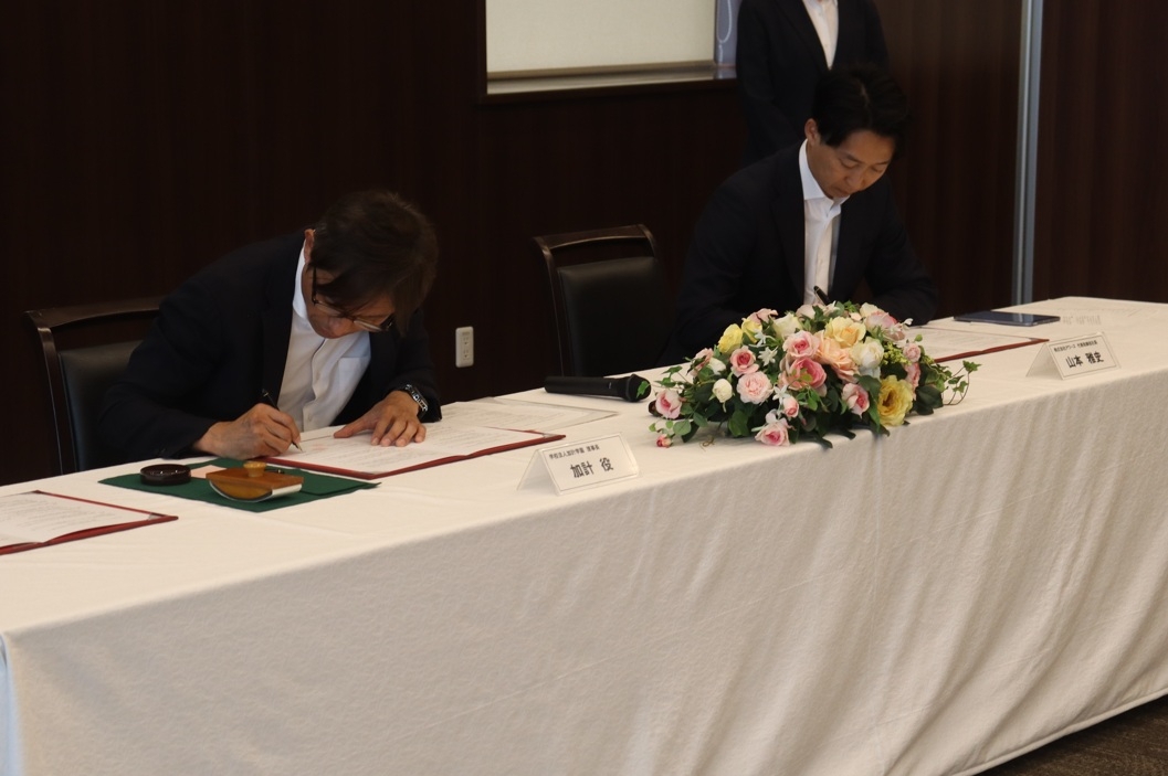 協定書に署名する(左から)加計理事長、山本社長