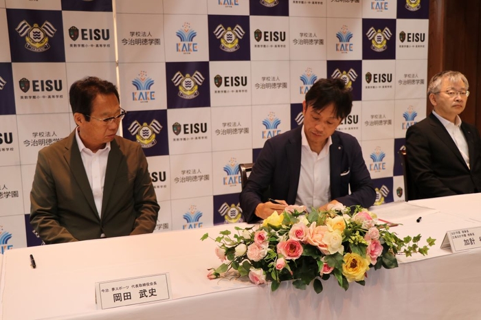 協定書に署名する加計理事長(中央)
