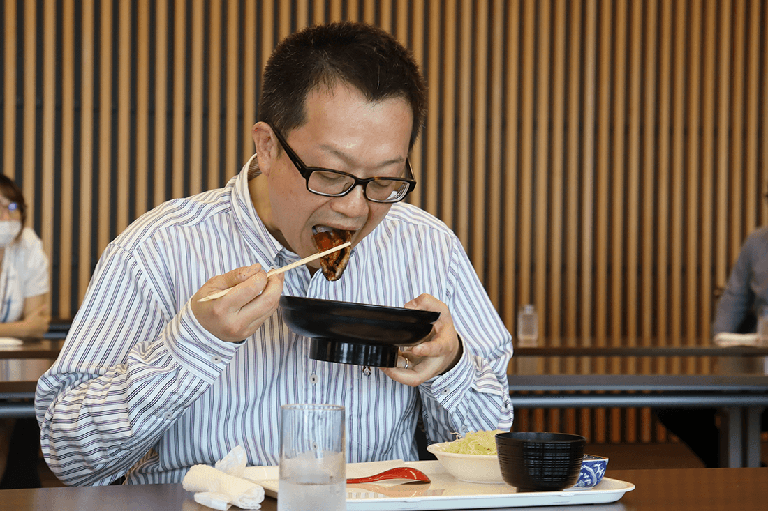 おいしそうにウナギを頬張る男性教員