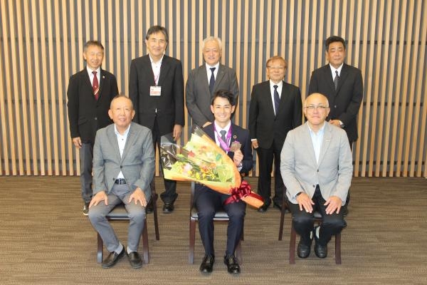 中西選手を中心に記念写真に納まる加計理事長(前列左)、大久保社長(前列右)、田原校長(後列左から2人目)、溝井総監督(後列左端)ら