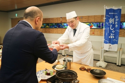 「夏限定 ながさき刺しゃぶ完成報告会」にて、 鈴木史朗長崎市長（左）へ新メニューを紹介する様子