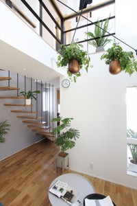 吹き抜けから自然光をとり込むアースの狭小住宅のリビングと、2階へ続くストリップ階段