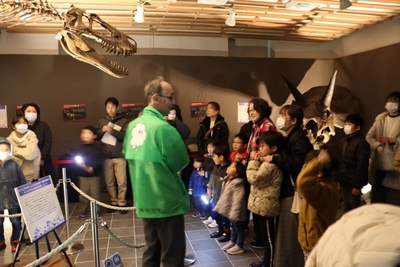 藤田館長（後ろ姿）の説明に聞き入るナイトツアー参加者