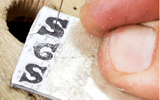 職人の手により一文字ずつ糸鋸(いとのこぎり)で切り出しを行います。数ミリ単位の非常に細かい作業を全て手作業で行います。 フォントはストロークを組み合わせて形作った、まっすぐな線が少ないデザインです。