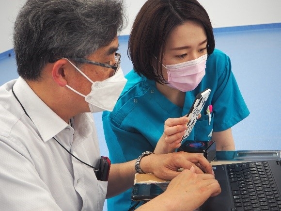 真剣な表情で赤木教授の説明を聞く佐伯講師(右)