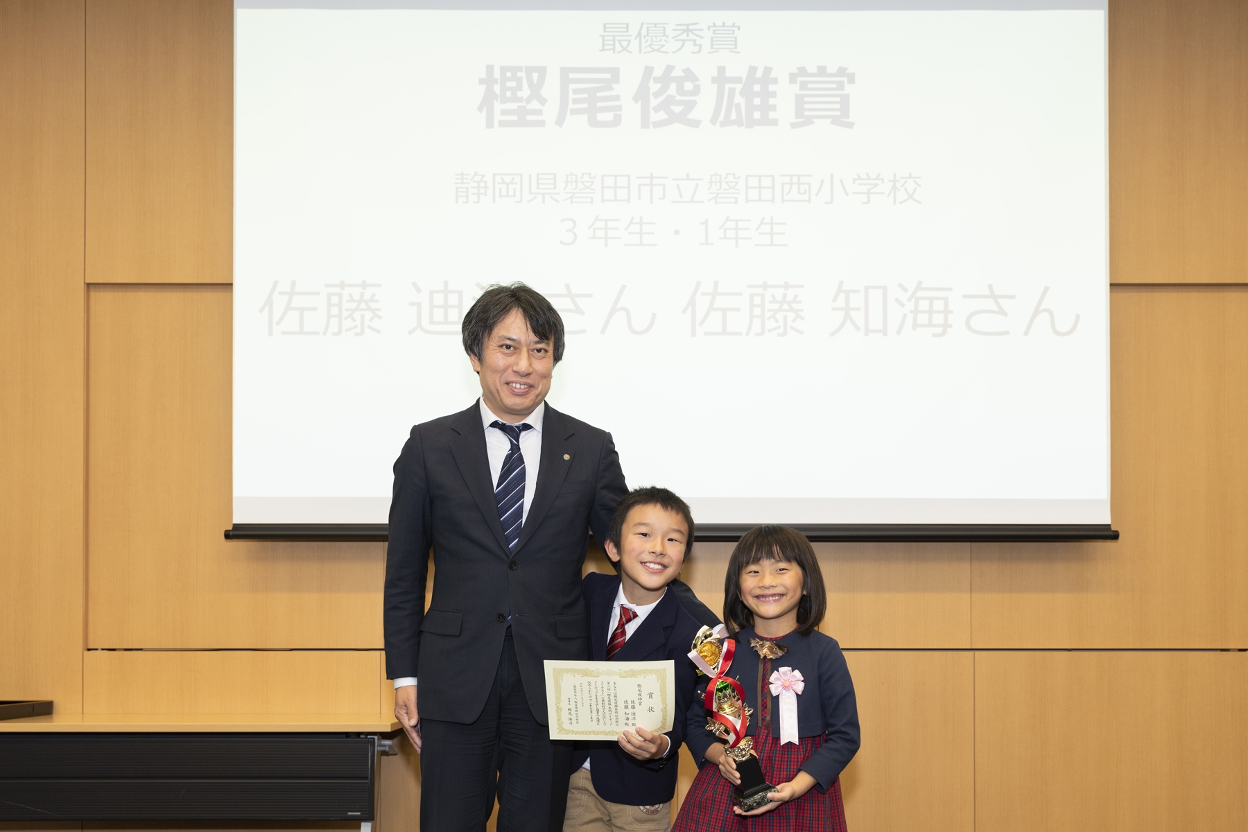 樫尾俊雄記念財団 樫尾隆司理事長と、樫尾俊雄賞を受賞した佐藤 迪洋さん・知海さん 記念写真