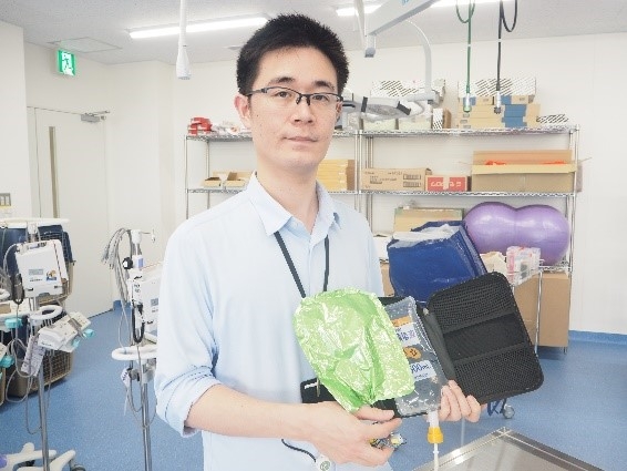 ポータブルタイプの点滴装置の試作機(3号機)を 手にする宮部助教
