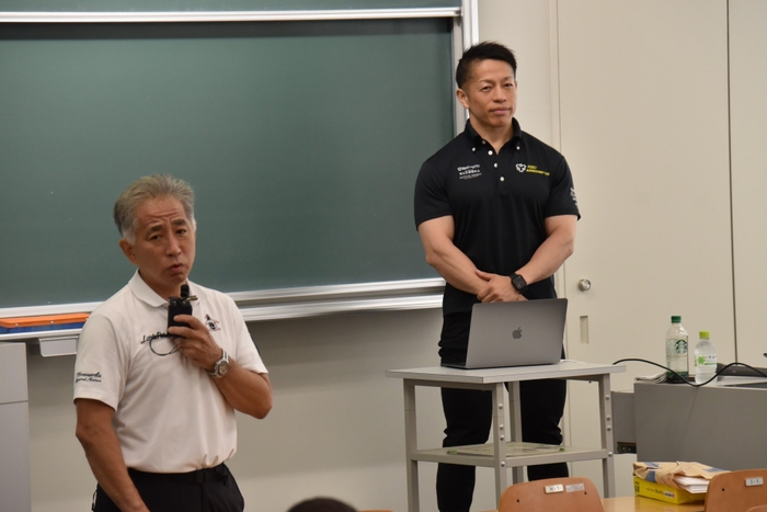 岡田教授を紹介する梅田教授(左)