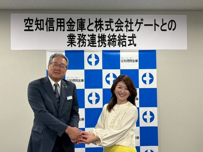 業務提携を締結し固い握手を交わす国井代表取締役(右)と熊尾理事長