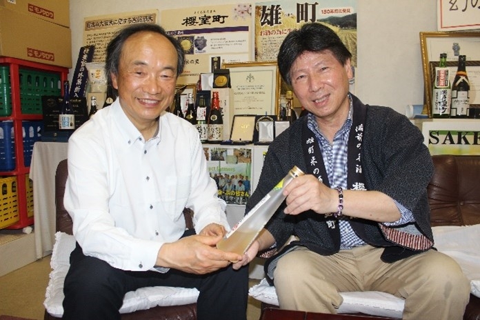サクラ酵母で造った日本酒を手にする滝澤教授(左)と花房社長(右)