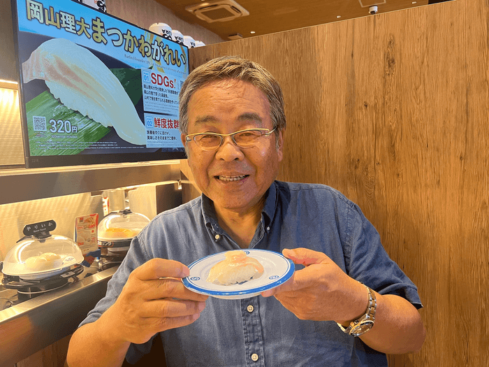 マツカワの握りを手に笑顔の山本准教授