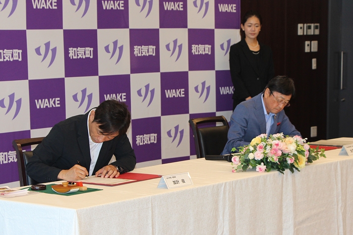 協定書に署名する(左から)加計理事長と太田町長