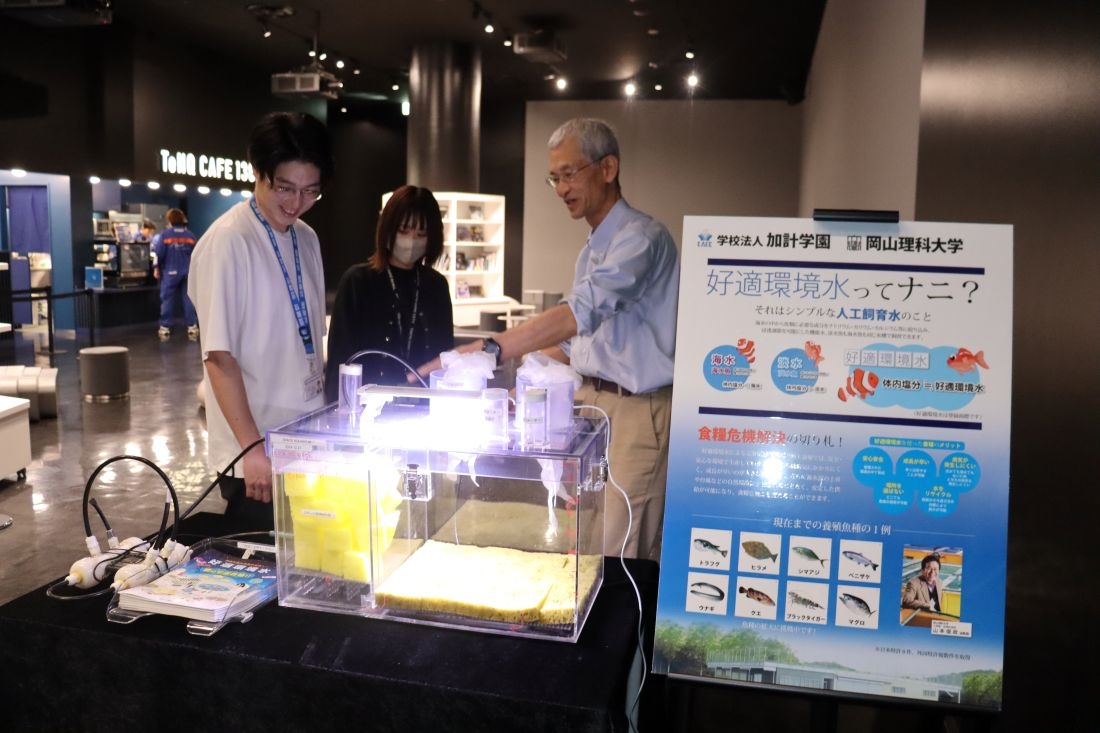 会場に水槽を設置してTeNQのスタッフと打ち合わせる津村誠一・生物生産教育研究センター招聘教授(右)=5月20日