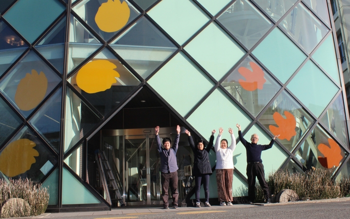 カッティングシートの取り付けが完了して喜ぶ学生たち。右端が石垣館長