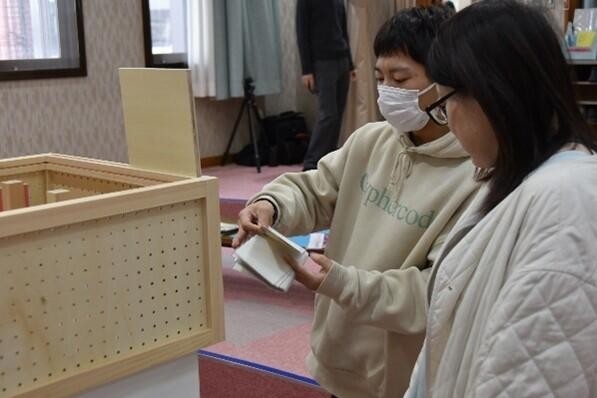 来場者に模型内の人の動きの意図を説明する西岡さん