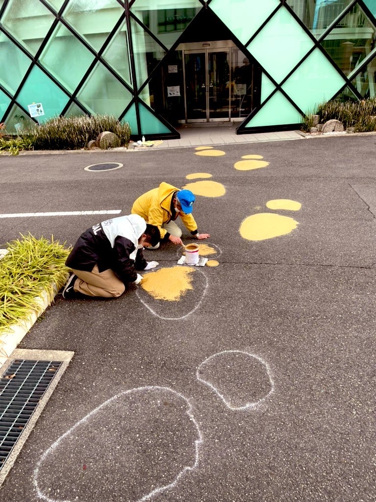 路面にペイントする石垣館長(右)と生物地球学科3年の岩本侑己さん=12月24日