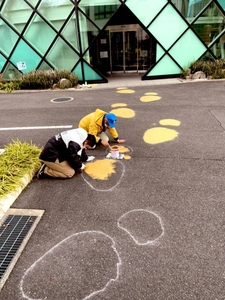 路面にペイントする石垣館長（右）と生物地球学科３年の岩本侑己さん＝12月24日