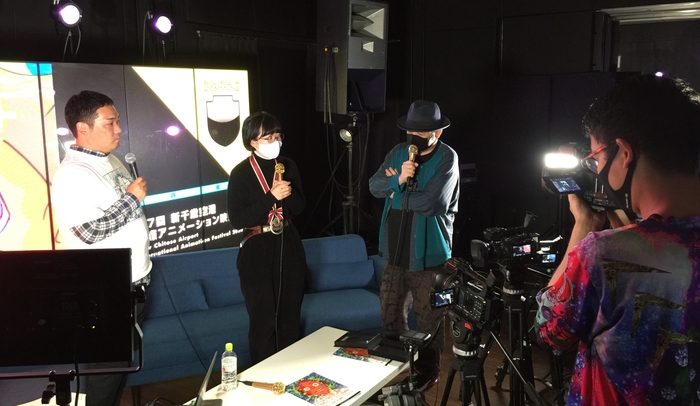 日本グランプリ ふるかわはらももか監督の授賞式の様子(SUPER DOMMUNEにて、左からフェスティバルディレクター 土居伸彰、ふるかわはらももか監督、国際審査員の宇川直宏氏)