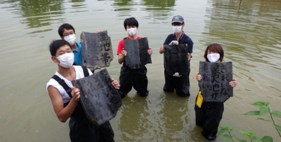 墨書きした古瓦を設置する様子（令和2年実施）