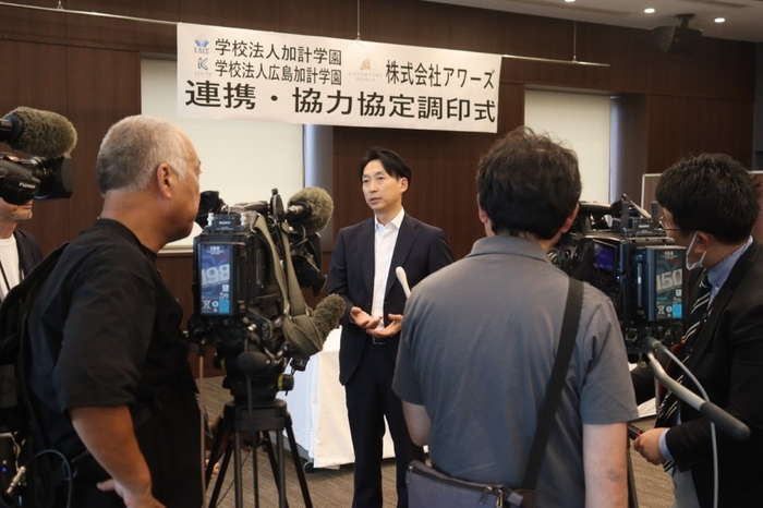 マスコミの囲み取材に答える山本社長(中央)