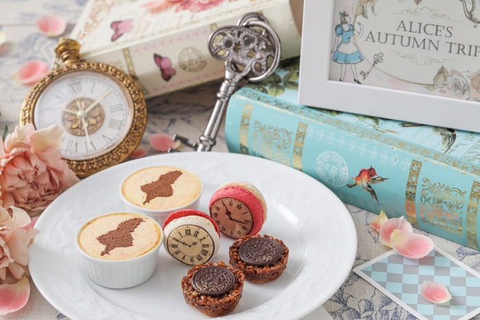 ▲スイーツスタンド下段イメージ: 落ち葉をイメージしたアーモンドキャラメルヌガーの“フロランタン”、林檎の果肉とキャラメル風味のバタークリームを使用した“林檎キャラメルマカロン時計”、秋色の背景にアリスのシルエットが可愛い“アリスのティラミス”