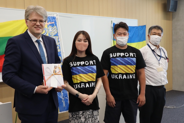 (左から)ジーカス大使、目録を手渡した安藤桃花さんと山田拓斗さん、稲葉教授