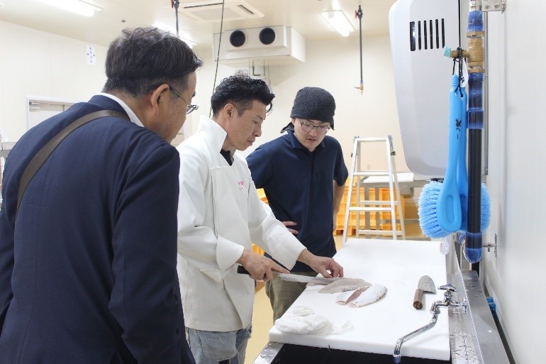 タマカイを調理する森下さん(中央)