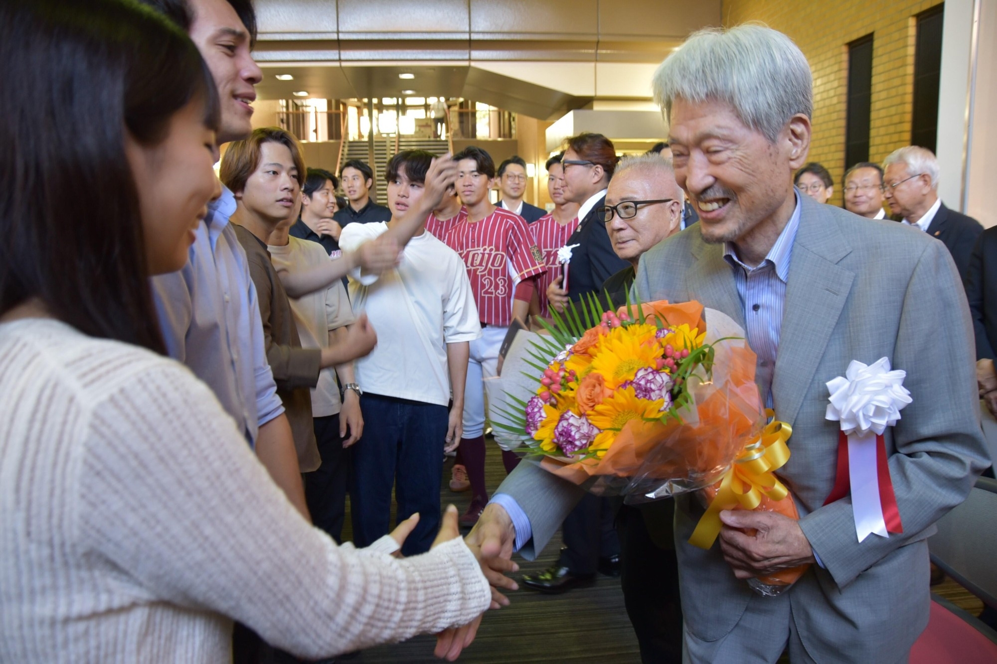 式後、学生たちと握手する長谷川顧問