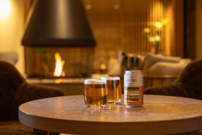 【ラウンジ】暖炉のやわらかな灯に包まれ、旅の疲れをそっとほぐしてくれるひととき。ゆらぐ光を眺めながら、クラフトビールとともにくつろぎの時間を──。