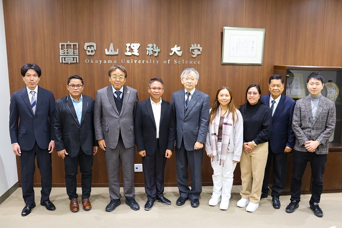 記念写真に納まるルイナタ統括部長(左から4人目)と平野学長(その右隣)ら