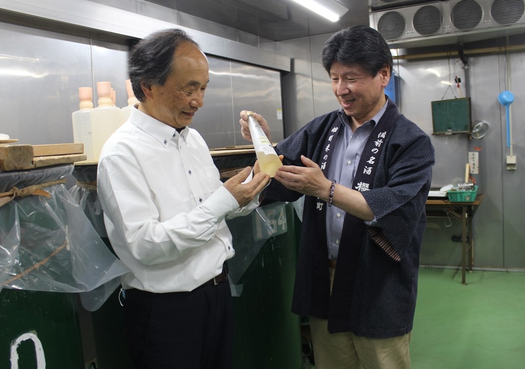 サクラ酵母で仕込んだタンクの前で出来具合を見る滝澤教授(左)と花房社長(右)