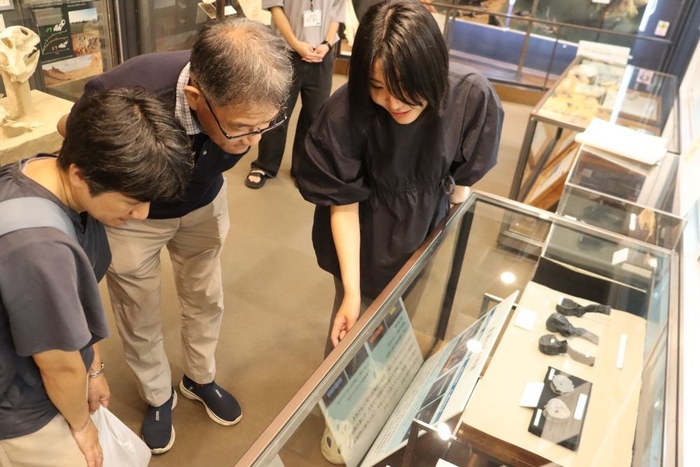 市川学芸員(右)の説明に聞き入る来館者