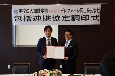 協定書を手にする（左から）加計理事長と尾崎会長