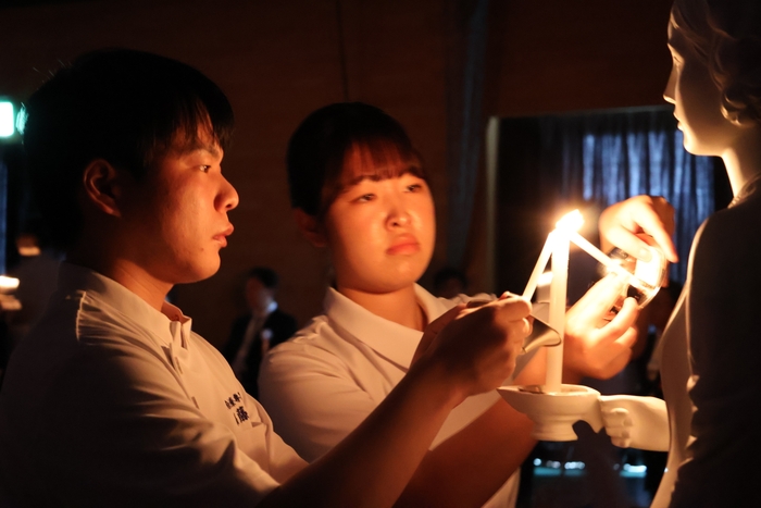 ナイチンゲール像から灯を受け取る学生