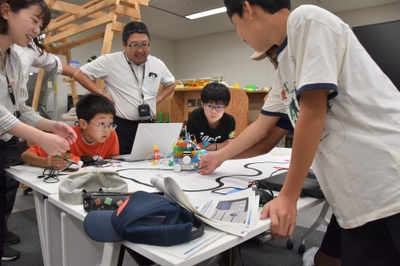 蛇行するコースでゴールできるかな？マシンの動きに注目する子供たち