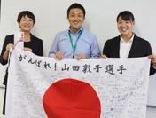 山田選手(左)にメッセージ入り国旗を渡す