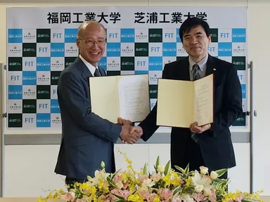 協定式で握手を交わす下村輝夫学長と村上雅人学長